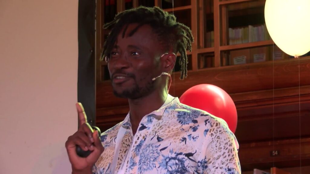 Bisi Alimi in a room speaking to people.